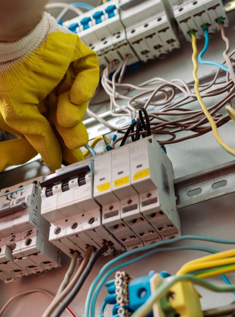 Low angle view of electrician in gloves fixing electrical distribution box